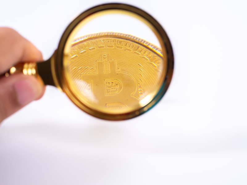 عکس ذره بین روی بخشی از بیت کوین