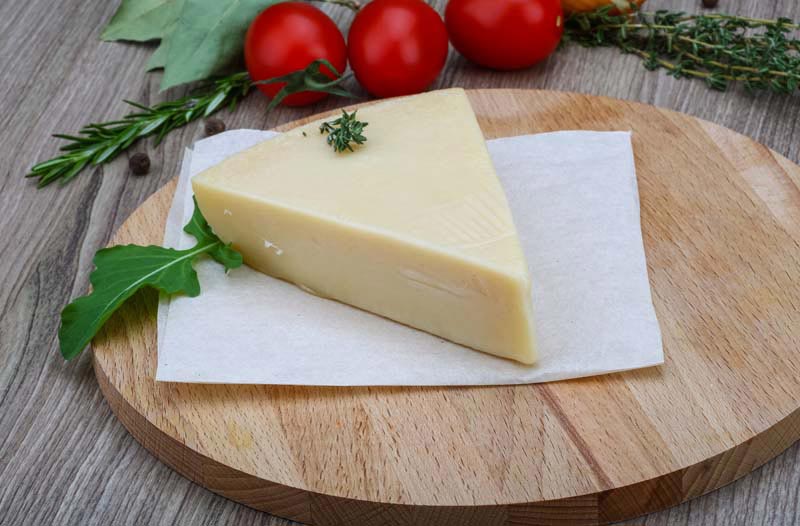 عکس لارج فرمت از یک قاچ پنیر کنار سبزی