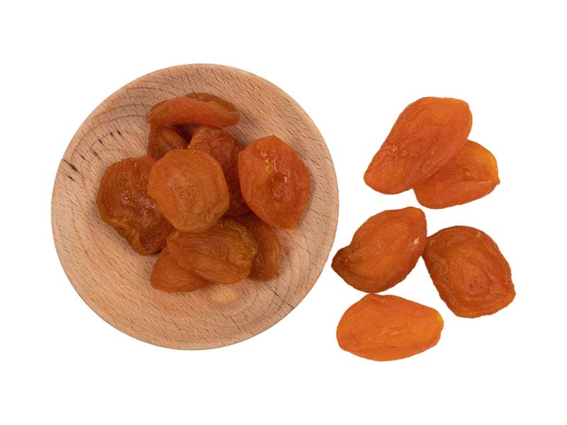 طرح بشقاب چوبی و زردآلو خشک از نمای بالا