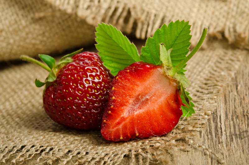 عکس زیبای توت فرنگی با برگ روی گونی