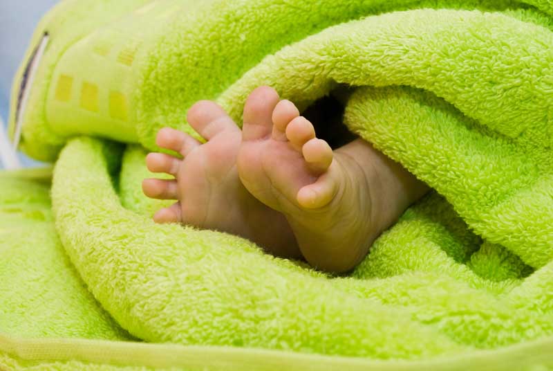 دانلود تصویر باکیفیت پای زیبای نوزاد روی پتوی سبز